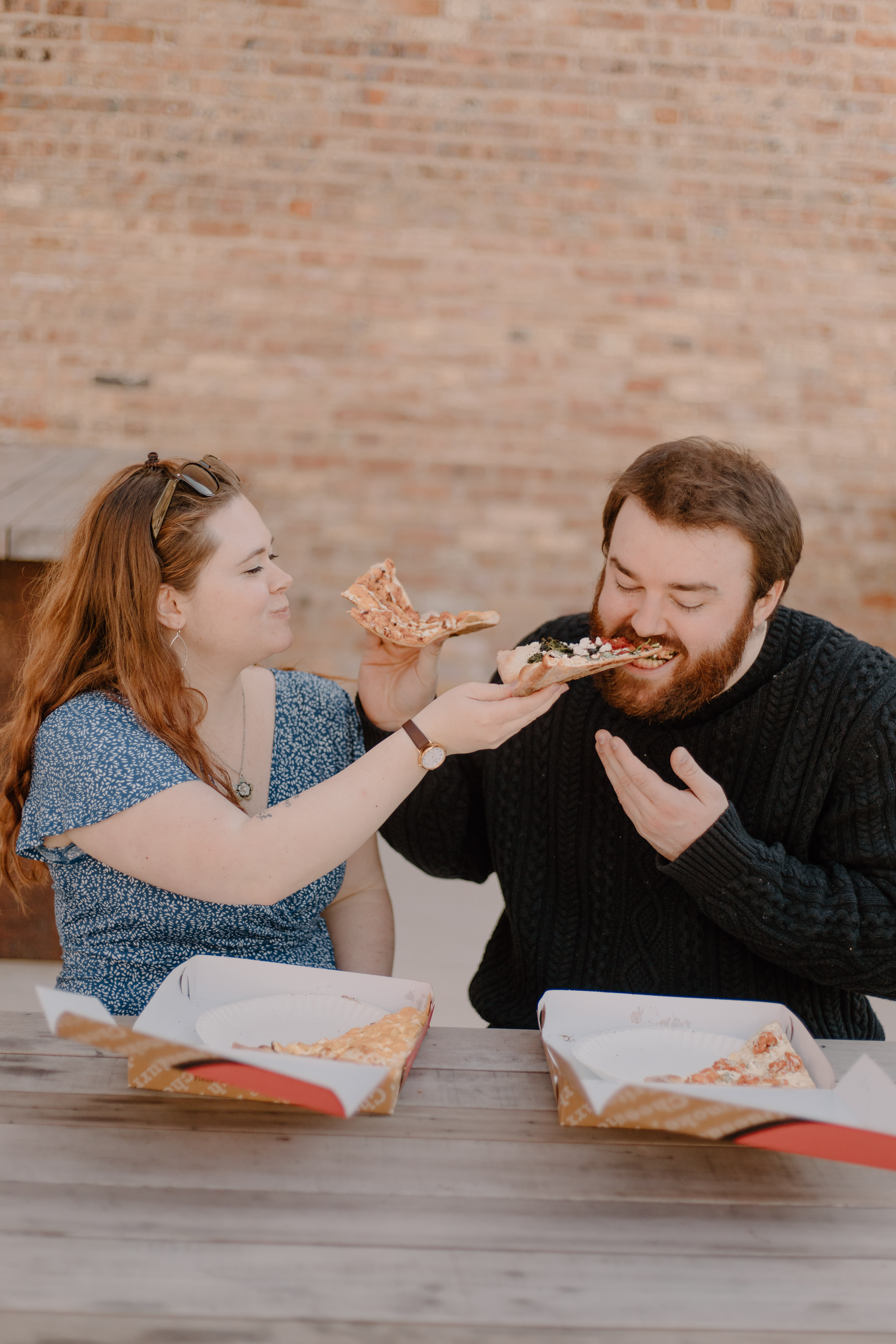 Couple feeds each other Ian's Pizza at engagement photo shoot