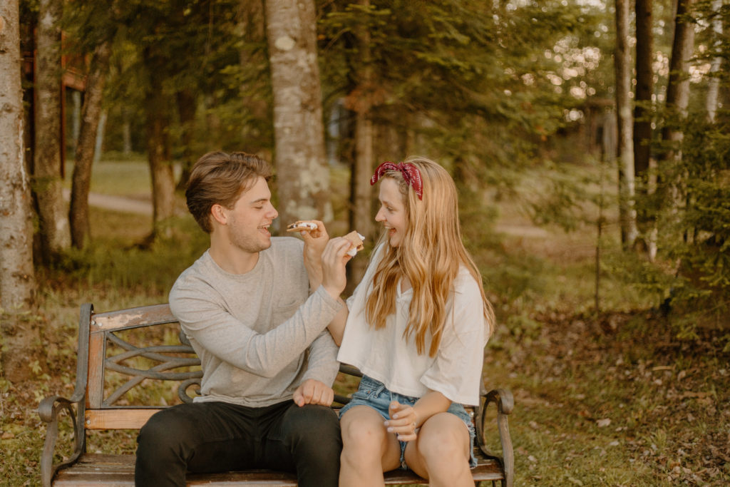 Guy and Girl feeding each other smores next to campfire
