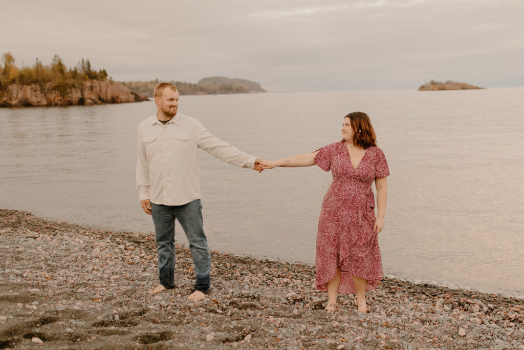 man and woman holding hands at lake superior