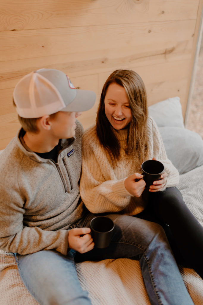 Couple Sitting on Airbnb Bed With Coffee