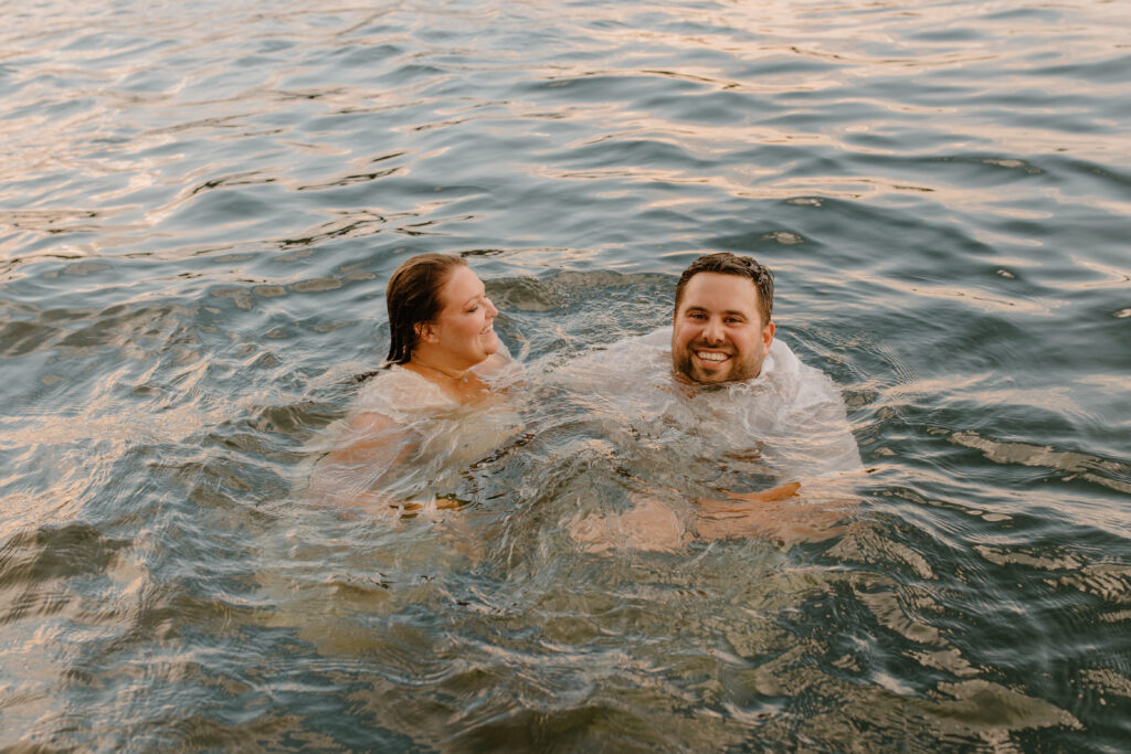 couple floating in water during engagement photos
