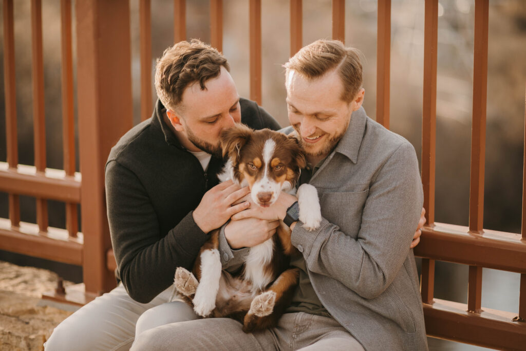 Two men cuddling their dog at the Stone Arch Bridge in Minneapolis, MN