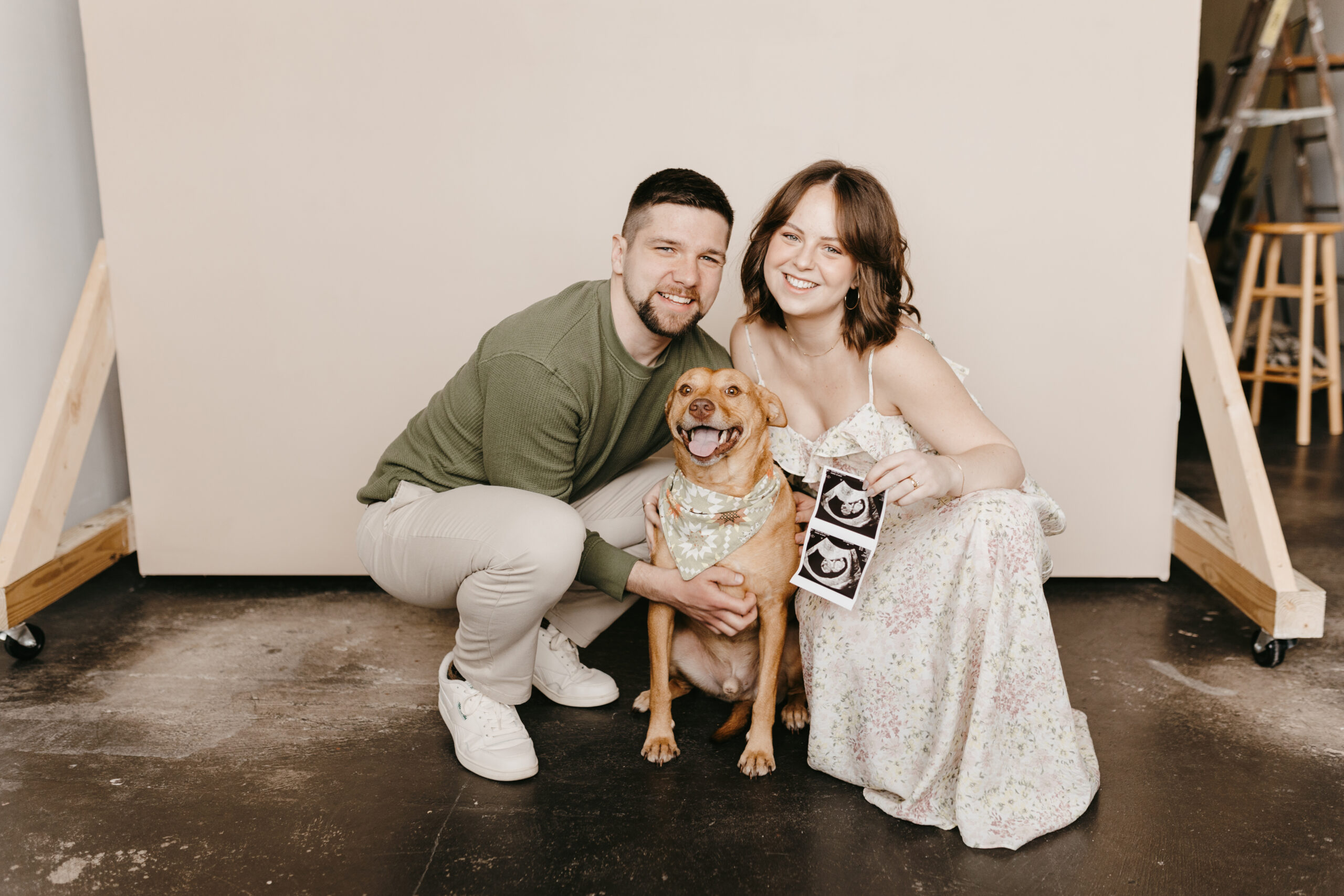 couple holding ultrasound photo with dog